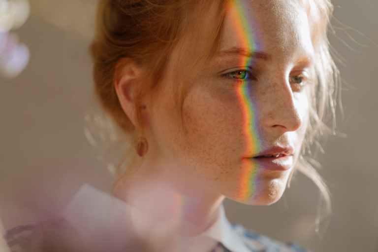 woman in white collared shirt with green blue and red face paint